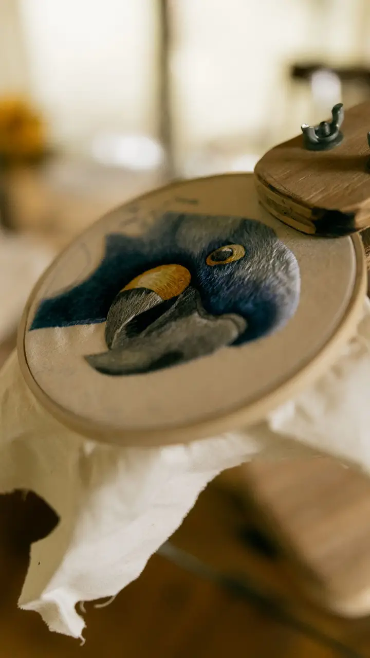 Colourful embroidered macaw in a wooden hoop